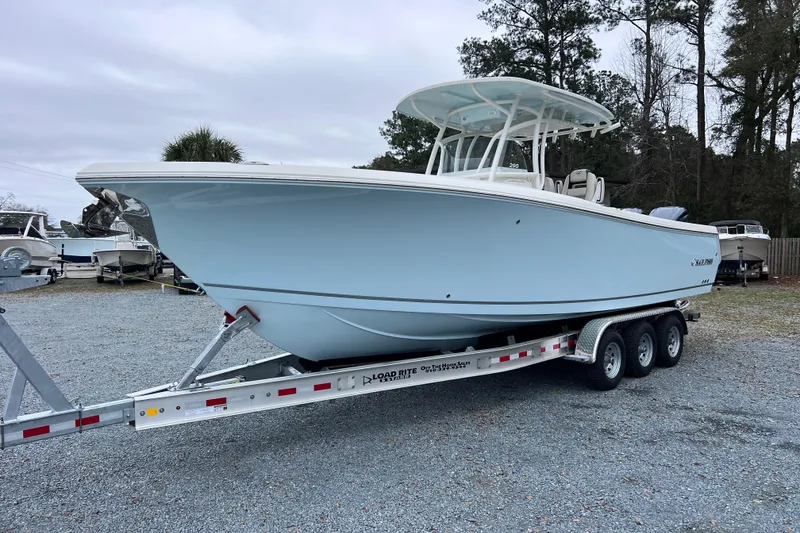 The Image of 2024 Sailfish 290 CC boat on a trailer, parked outdoors. - 0