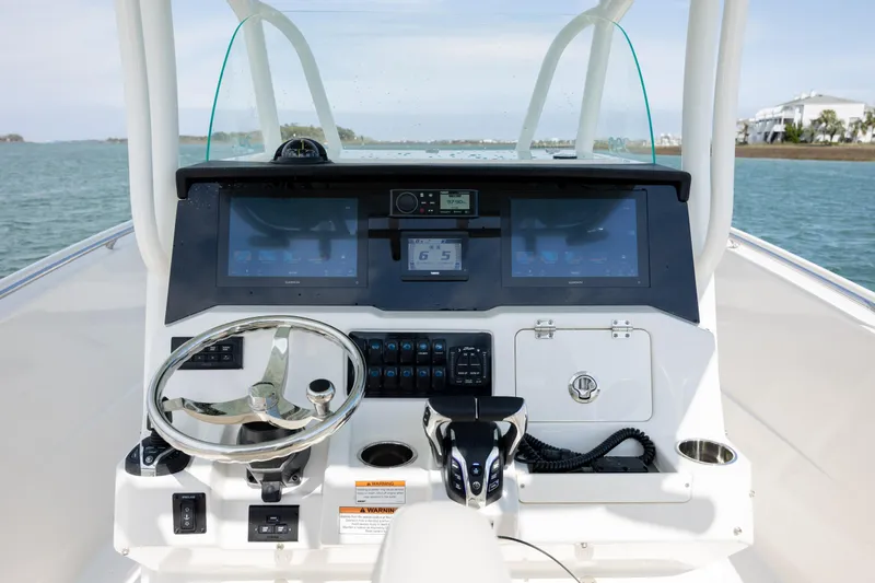 Slide: The Image of 2024 Sailfish 290 CC boat dashboard with modern navigation controls and dual displays on open water. - 19