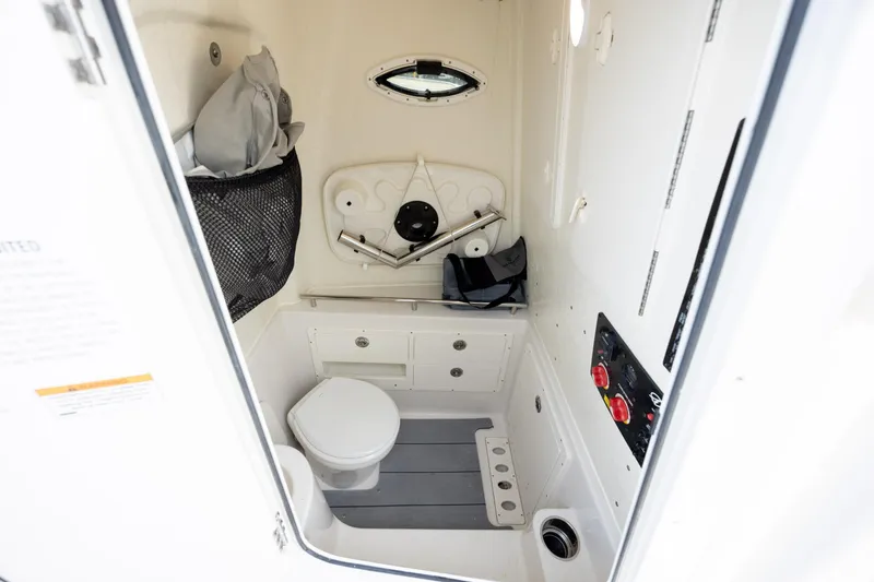 Slide: The Image of 2024 Sailfish 290 CC boat interior with compact marine toilet and storage. - 23