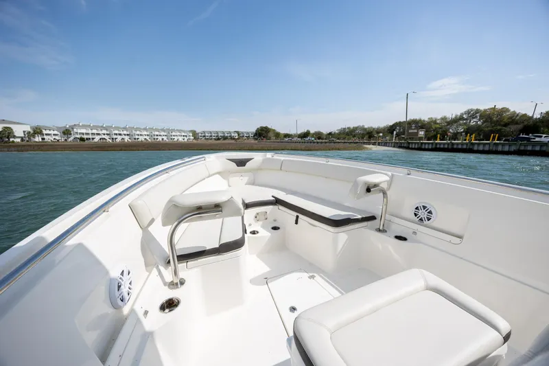 Slide: The Image of 2024 Sailfish 290 CC boat interior with seating, on calm water near shoreline. - 24