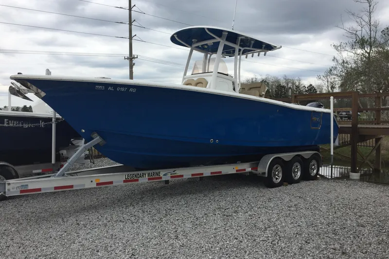 Slide: The Image of 2016 Sea Hunt Gamefish 27 boat on trailer, blue hull, overcast sky. - 33