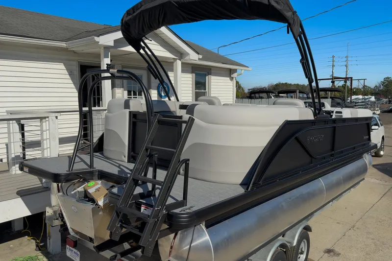 Slide: The Image of 2026 Godfrey Sweetwater 22' Split Bench Tritoon boat with ladder and canopy, docked near a house. - 20