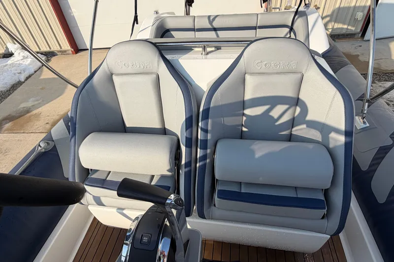 Slide: The Image of 2023 Cobra Ribs Nautique 7.0m boat interior with dual gray seats and steering wheel. - 10