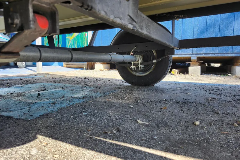 Slide: The Image of Underneath view of 2025 Tracker Grizzly 1654 MVX Sportsman trailer axle and wheel. - 12
