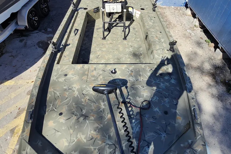 Slide: The Image of 2025 Tracker Grizzly 1654 MVX Sportsman boat with camouflage design, docked outdoors. - 15