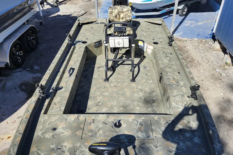 Slide: The Image of 2025 Tracker Grizzly 1654 MVX Sportsman boat with camouflage design, parked outdoors. - 16