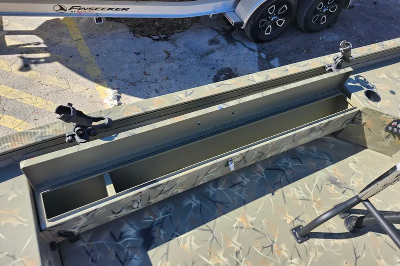 Slide: The Image of 2025 Tracker Grizzly 1654 MVX Sportsman boat with open storage compartment and camouflage design. - 23