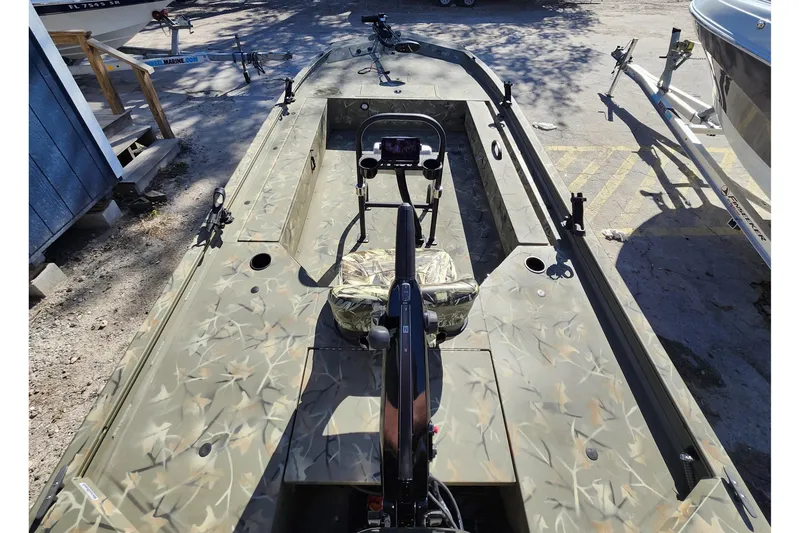 Slide: The Image of 2025 Tracker Grizzly 1654 MVX Sportsman boat with camouflage design, parked outdoors. - 31