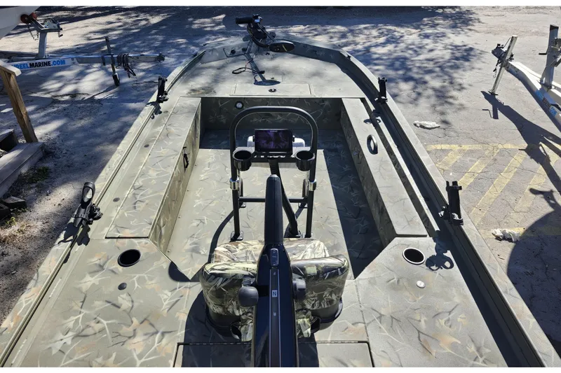 Slide: The Image of 2025 Tracker Grizzly 1654 MVX Sportsman boat with camouflage interior, parked on pavement. - 32