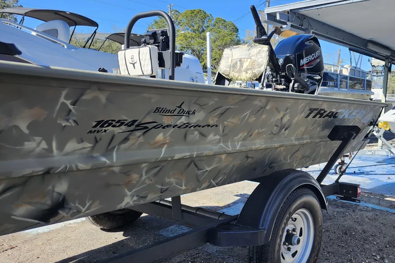 Slide: The Image of 2025 Tracker Grizzly 1654 MVX Sportsman boat with camouflage design on a trailer. - 4