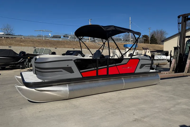 The Image of 2026 Sylvan R-22 LZ DH pontoon boat with red and gray design on a sunny day. - 0