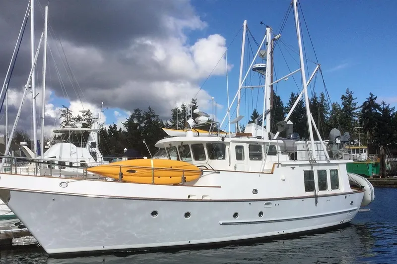 Slide: The Image of Nordhavn 46 yacht, 2001 model, docked with kayaks on deck, under cloudy sky. - 1