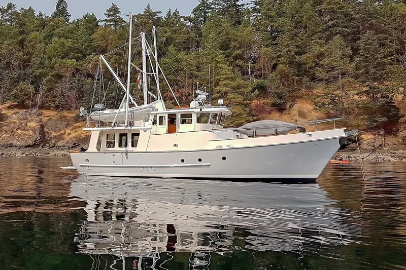 Slide: The Image of 2001 Nordhavn 46 yacht anchored near forested shoreline, reflecting on calm water. - 71