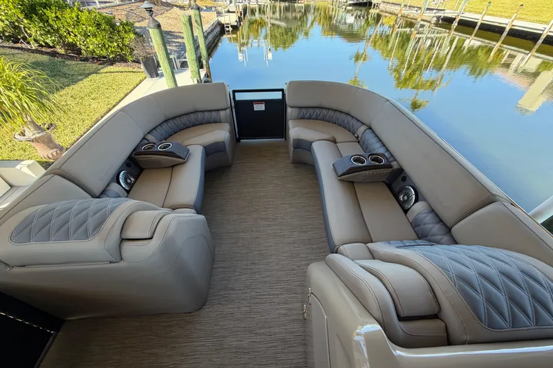 Slide: The Image of Luxurious seating on 2024 Bennington 25 QX Swingback pontoon boat, docked by calm waters. - 17