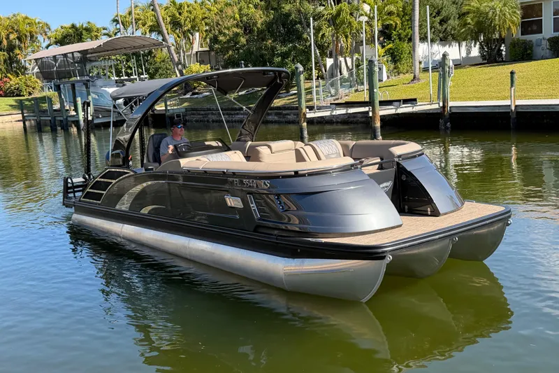 Slide: The Image of 2024 Bennington 25 QX Swingback pontoon boat on calm water, featuring sleek design and luxury seating. - 3