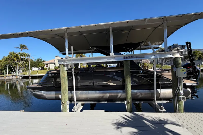 Slide: The Image of 2024 Bennington 25 QX Swingback pontoon boat on a lift by a dock. - 32