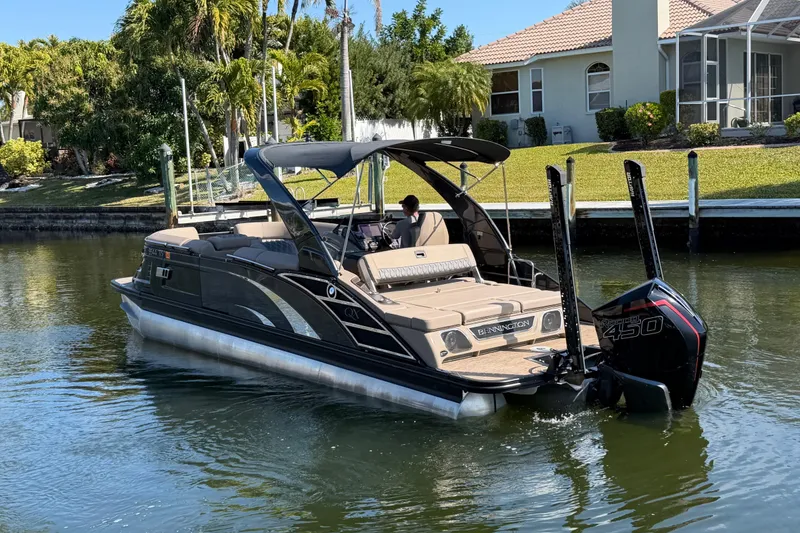 Slide: The Image of 2024 Bennington 25 QX Swingback pontoon boat cruising on a calm waterway. - 4