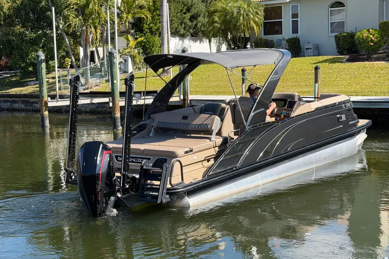 Slide: The Image of 2024 Bennington 25 QX Swingback pontoon boat cruising on a calm waterway. - 5