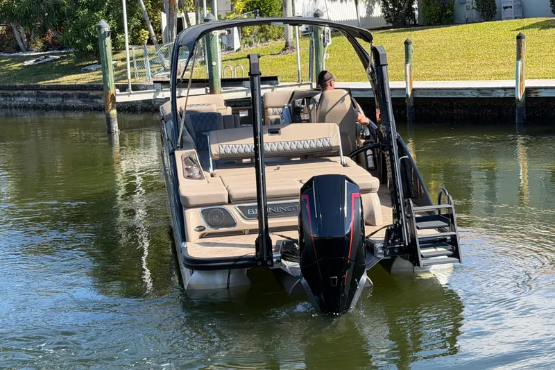 Slide: The Image of 2024 Bennington 25 QX Swingback boat navigating a calm waterway. - 6