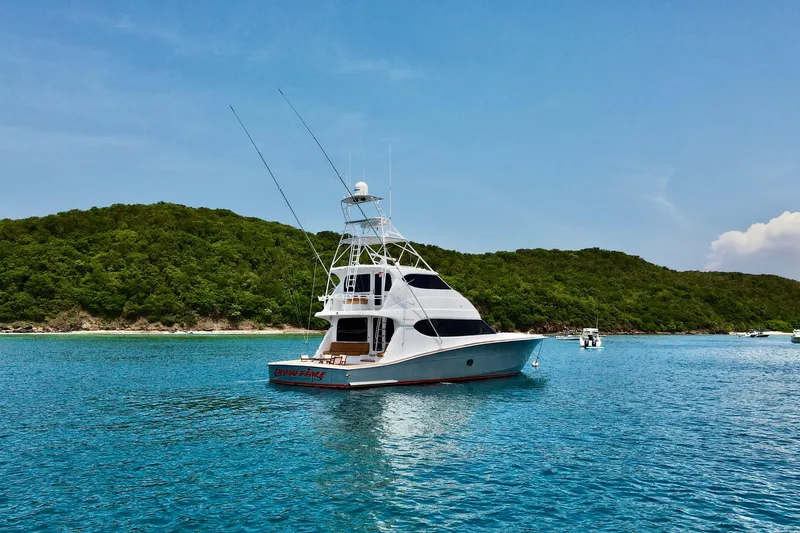 Slide: The Image of 2007 Hatteras 68 Convertible yacht on clear blue water near lush green island. - 31