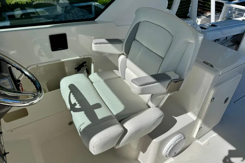 Slide: The Image of 2020 Pursuit DC 266 Dual Console boat interior with plush captain's chair and steering wheel. - 10
