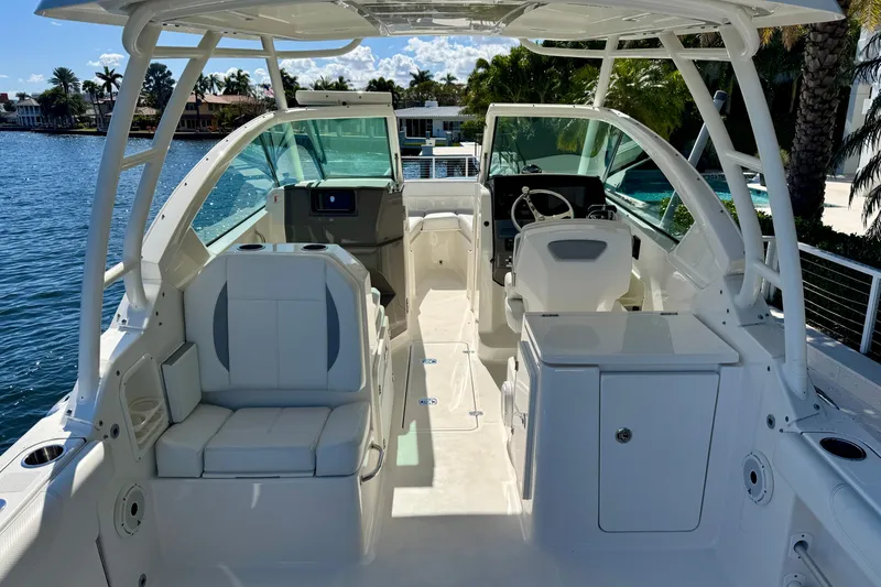 Slide: The Image of 2020 Pursuit DC 266 Dual Console boat interior with seating and steering wheel, docked by water. - 2
