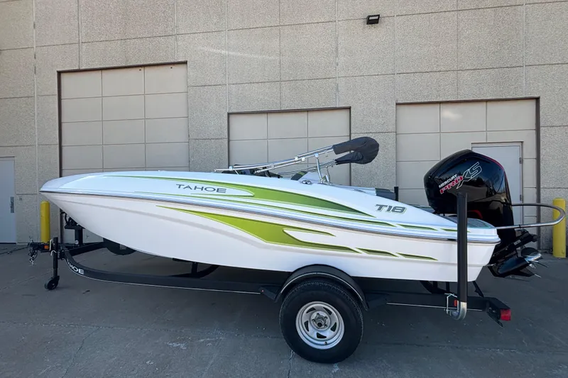 The Image of 2023 Tahoe T18 boat with green accents on a trailer, parked outdoors. - 2