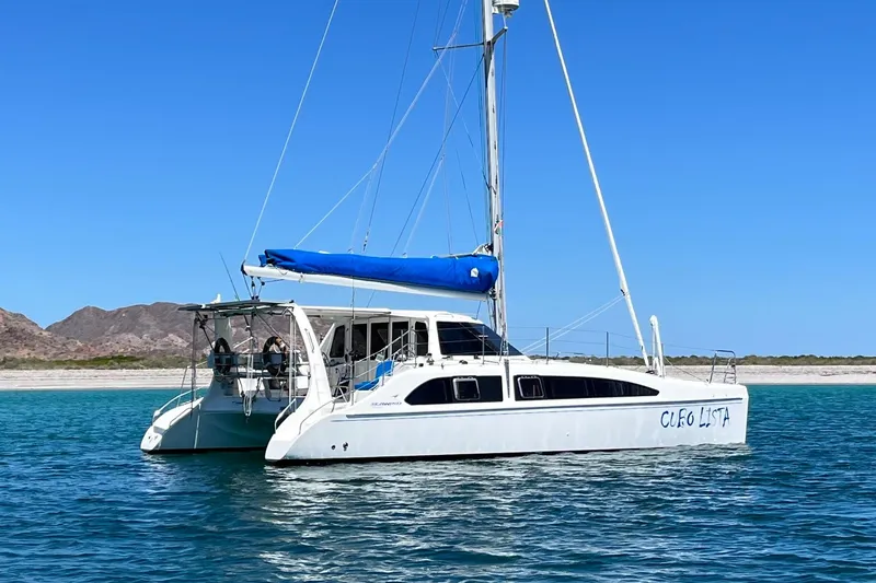 The Image of 2008 Seawind 1160 catamaran sailing in clear blue waters near a scenic coastline. - 0