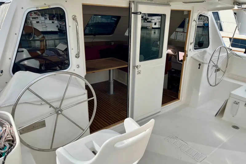 Slide: The Image of 2008 Seawind 1160 catamaran cockpit with dual steering wheels and open cabin view. - 20