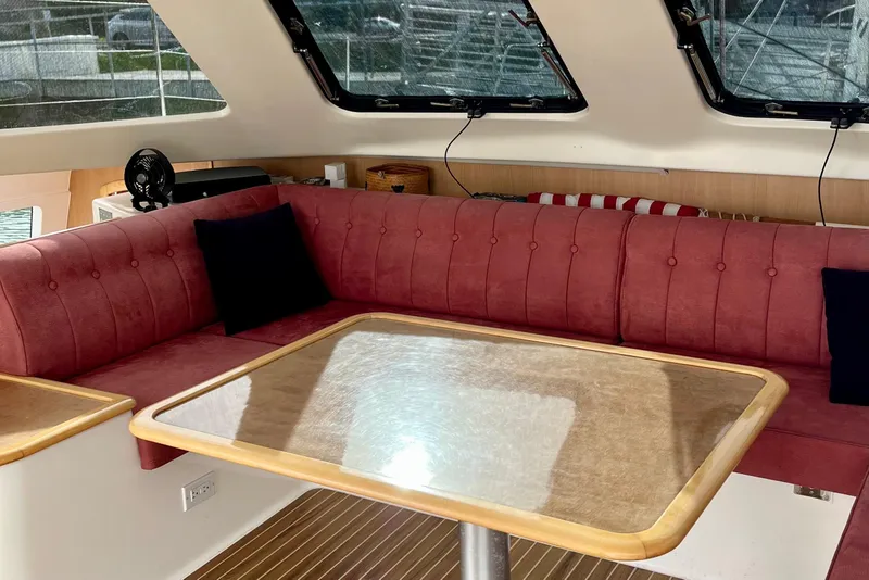 Slide: The Image of Interior of 2008 Seawind 1160 catamaran with red seating and wooden table. - 6