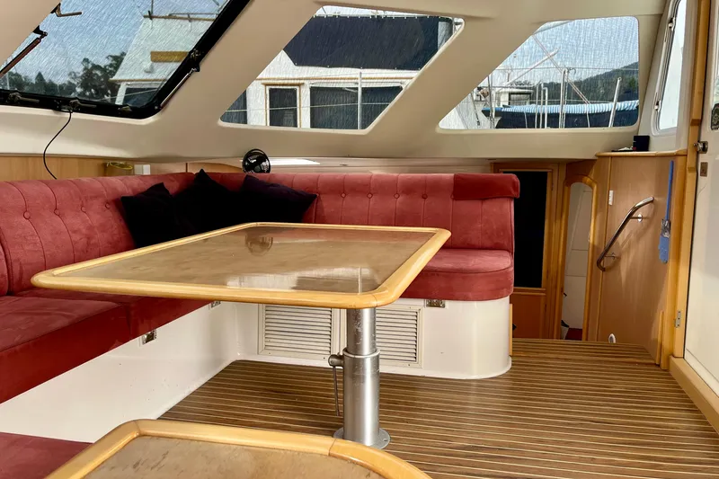 Slide: The Image of Interior of 2008 Seawind 1160 catamaran with red seating and wooden table. - 7