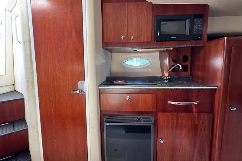 Slide: The Image of 2002 Sport-Craft 3150 Sportfish interior with kitchenette, featuring wood cabinetry and appliances. - 33