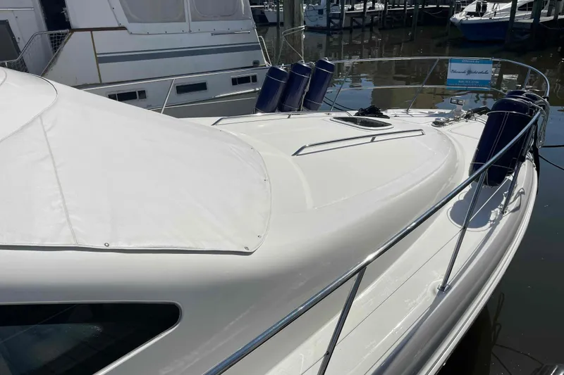 Slide: The Image of 2005 Sea Ray 420 Sedan Bridge yacht docked, featuring sleek white deck and protective railings. - 107