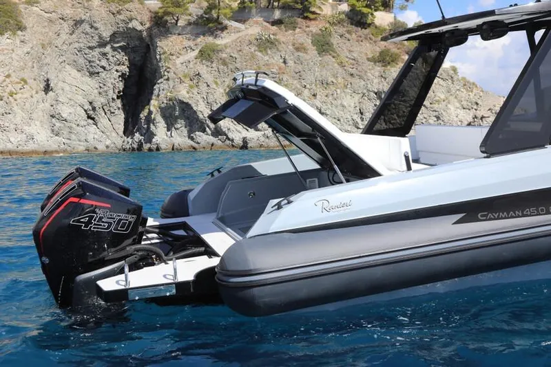 Slide: The Image of 2026 Ranieri Cayman 45.0 Executive boat on clear blue water near rocky coastline. - 5