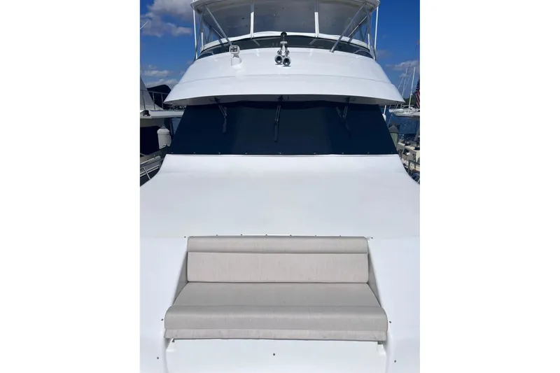 Slide: The Image of 2001 Hatteras 75 Cockpit Motor Yacht with cushioned seating on deck, under clear blue sky. - 16