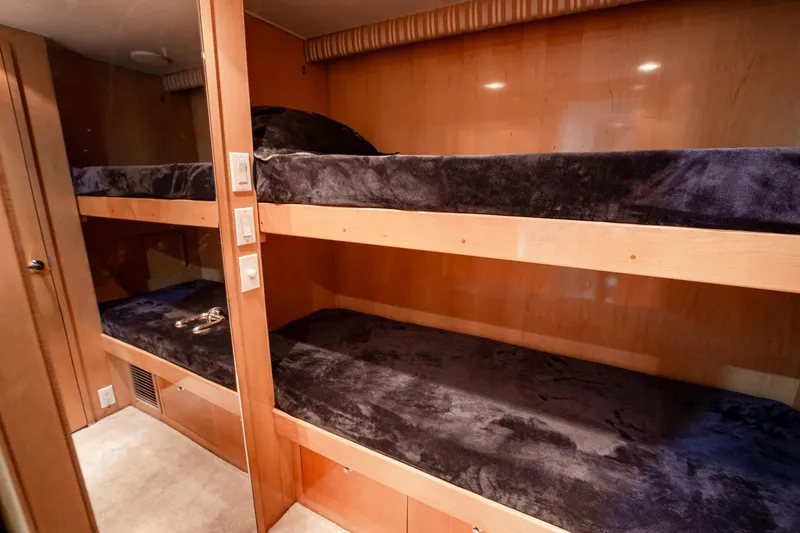 Slide: The Image of Bunk beds in 2001 Hatteras 75 Cockpit Motor Yacht cabin, featuring plush bedding and wood paneling. - 26