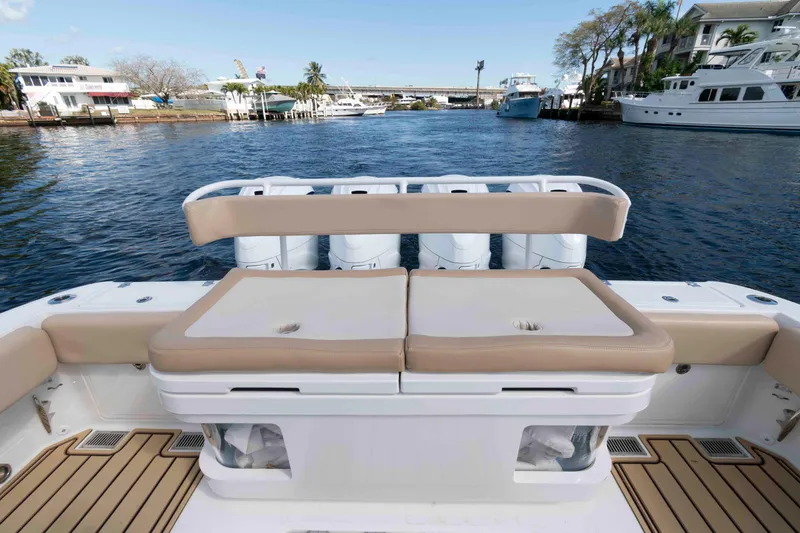 Slide: The Image of 2021 HCB 53 Sueños boat deck with tan seating and wooden flooring, docked near a bridge. - 23