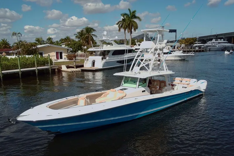 Slide: The Image of 2021 HCB 53 Sueños boat docked in a marina, surrounded by palm trees and yachts. - 2