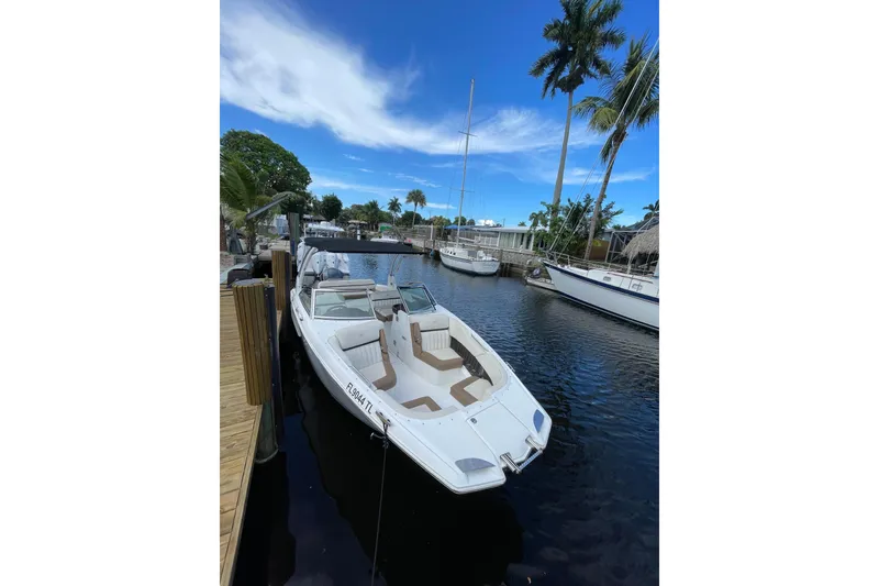 The Image of 2021 Cobalt 25SC boat docked in a scenic marina with palm trees. - 1