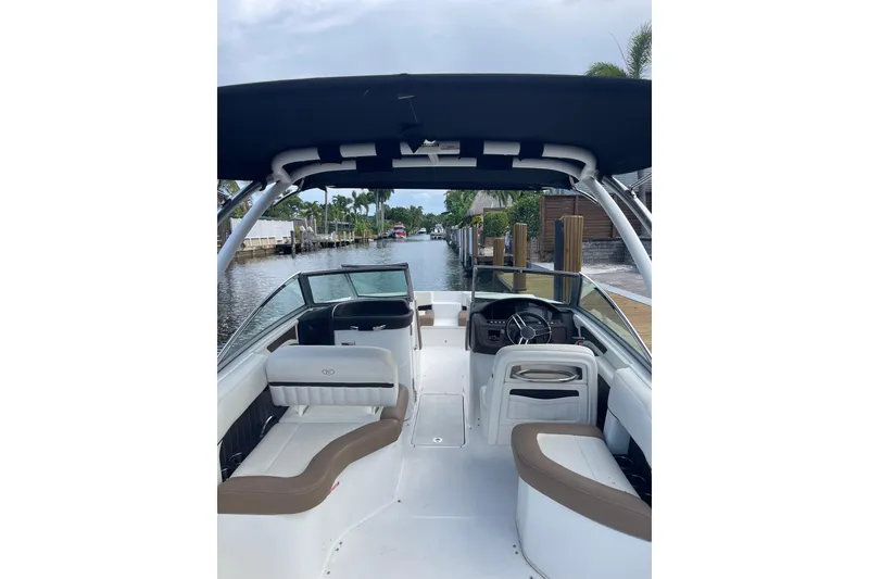 Slide: The Image of 2021 Cobalt 25SC boat interior with seating and steering, docked by a canal. - 11