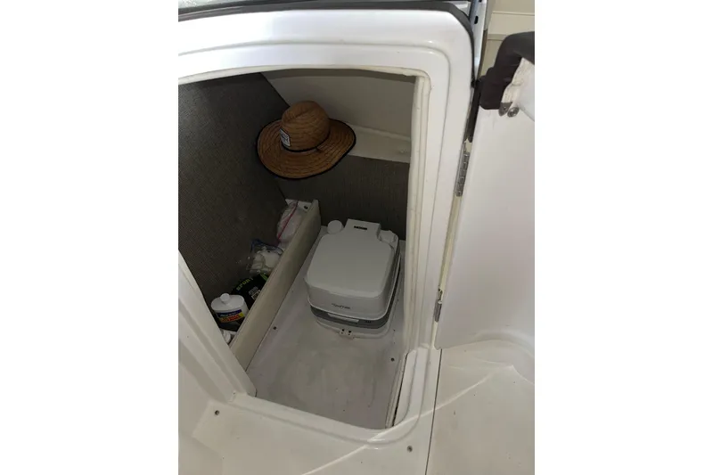 Slide: The Image of 2021 Cobalt 25SC boat interior with storage compartment and portable toilet. - 16