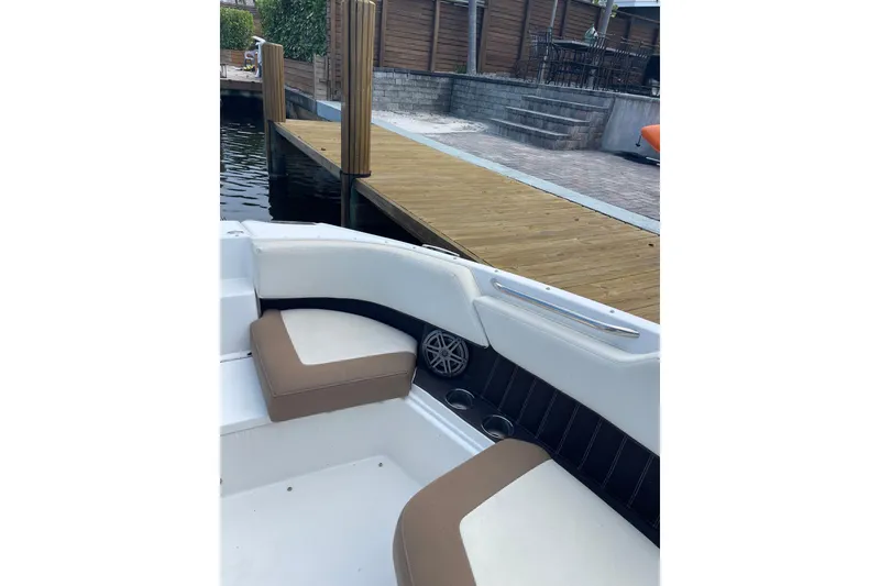 Slide: The Image of 2021 Cobalt 25SC boat interior with cushioned seating near a wooden dock. - 5