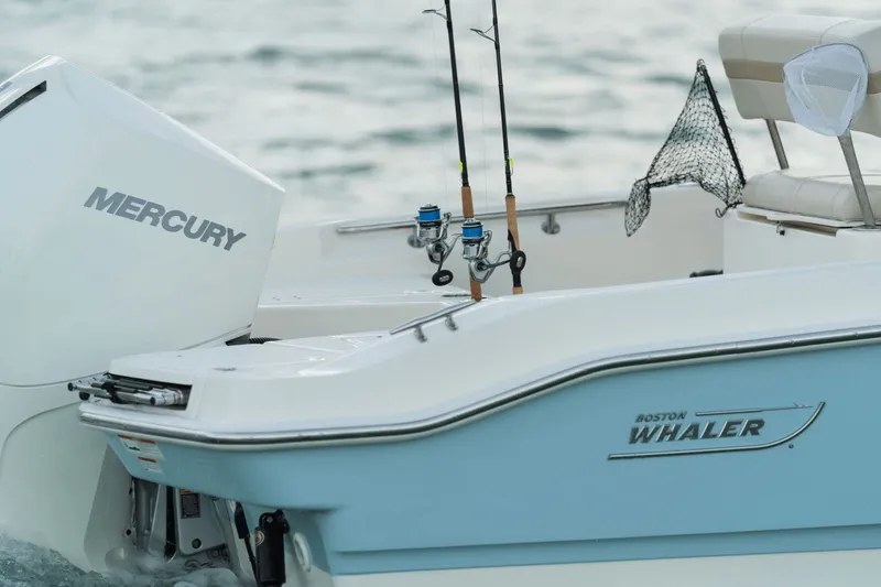 Slide: The Image of The image shows the stern of a Boston Whaler 220 Dauntless boat with fishing rods and a Mercury engine. - 43
