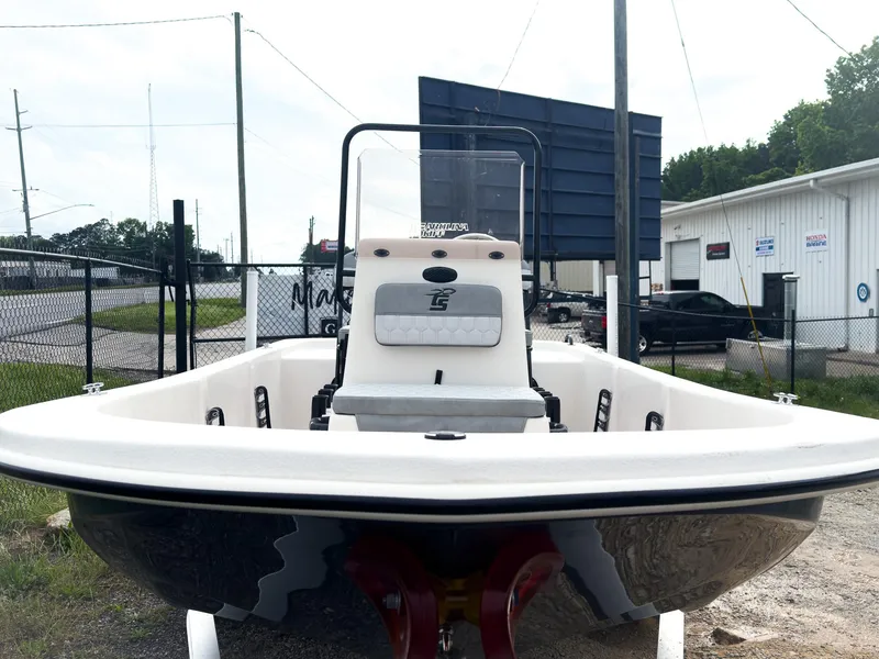 Slide: The Image of 2025 Carolina Skiff 16 JVX CC boat, front view, parked outdoors near industrial buildings. - 6