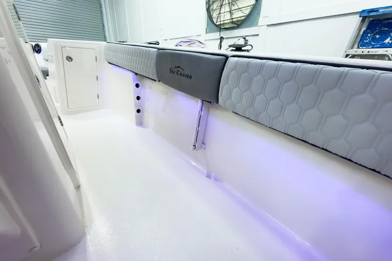 Slide: The Image of 2026 Sea Chaser 27 HFC CC boat interior with cushioned seating and ambient lighting. - 31