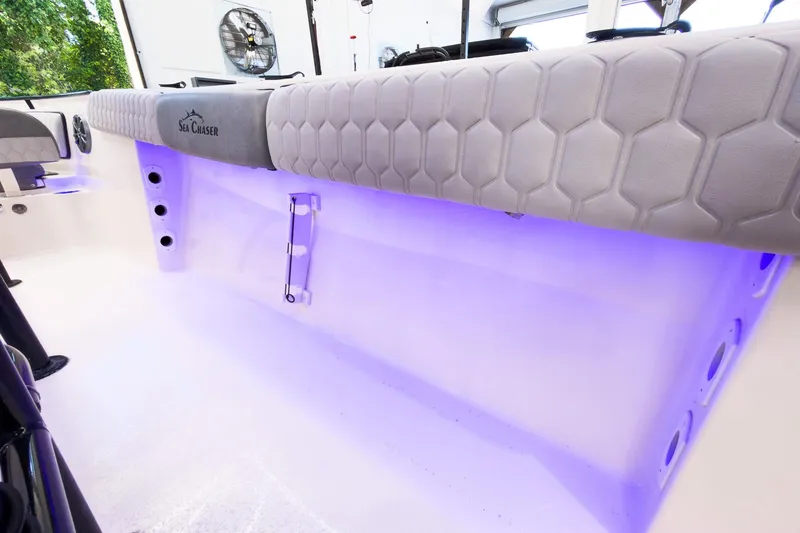 Slide: The Image of 2026 Sea Chaser 22 HFC boat interior with purple LED lighting and cushioned seating. - 28