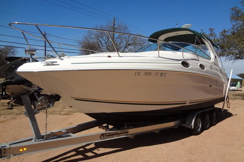 The Image of 2002 Sea Ray Sundancer 280 boat on trailer, parked outdoors under clear blue sky. - 0