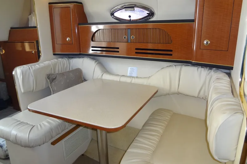 Slide: The Image of Interior of 2002 Sea Ray Sundancer 280, featuring a cozy dining area with cushioned seating. - 28