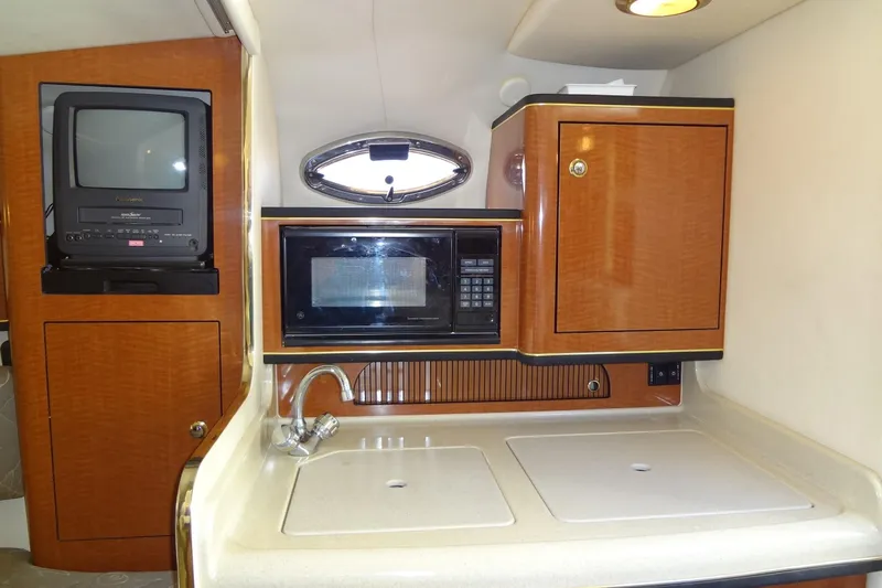 Slide: The Image of 2002 Sea Ray Sundancer 280 interior with kitchenette, featuring microwave, sink, and TV. - 33