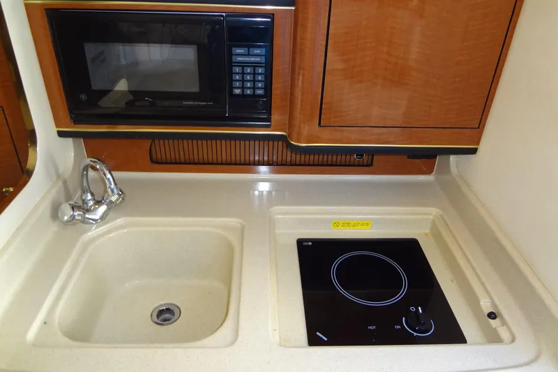 Slide: The Image of 2002 Sea Ray Sundancer 280 galley with sink, microwave, and stovetop. - 34